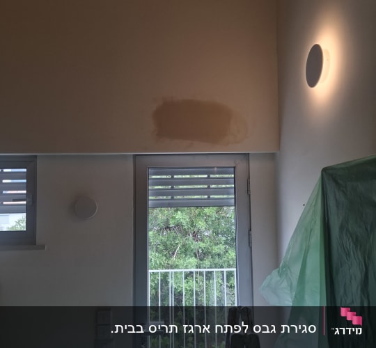 עבודת תיקון ושפכטל על גבי קיר גבס מעל דלת יציאה